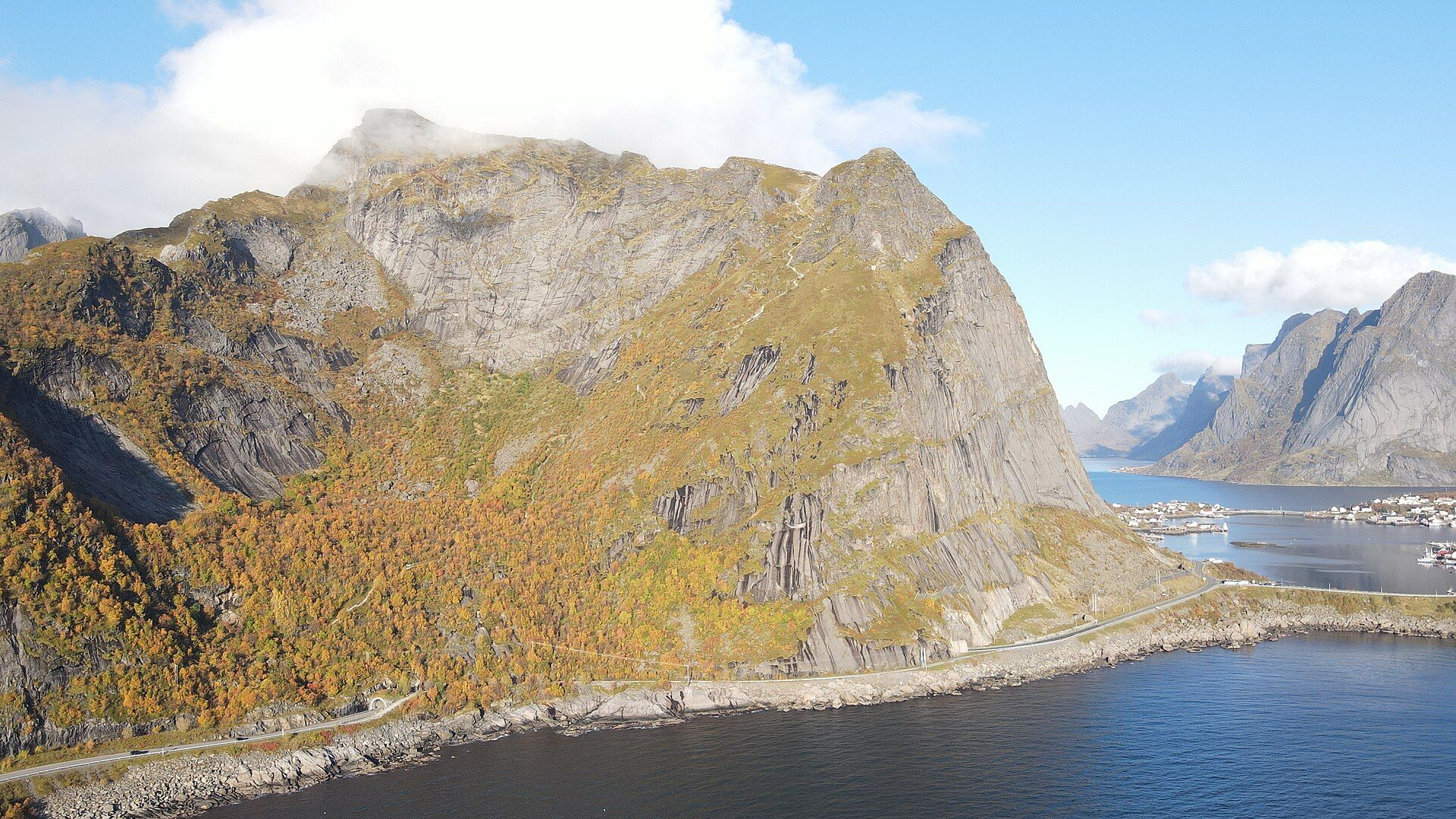 Reinebringen mountain with orange autumn birch on its lower slopes above the sea at Reine