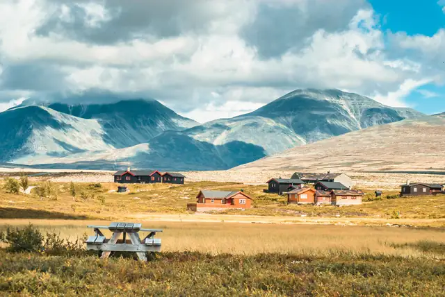 Picturesque Nordic cabins surrounded by mountains in Kvam, Norway, showcasing serene rural beauty.