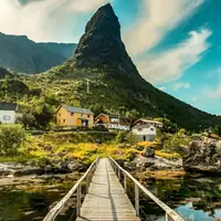 Explore the picturesque landscape of Vågan, Nordland with a stunning wooden bridge leading to colorful houses.