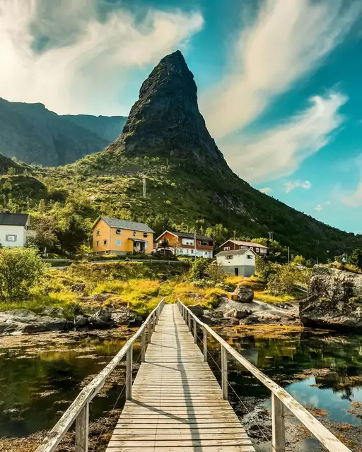 Explore the picturesque landscape of Vågan, Nordland with a stunning wooden bridge leading to colorful houses.
