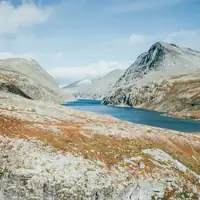 Discover the serene beauty of Norway's rugged mountains and tranquil lake.