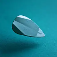 A detailed close-up of a levitating guitar pick against a teal background, showcasing texture.
