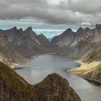 Stunning view of dramatic fjord and mountains near Reine, Norway, under cloudy sky.