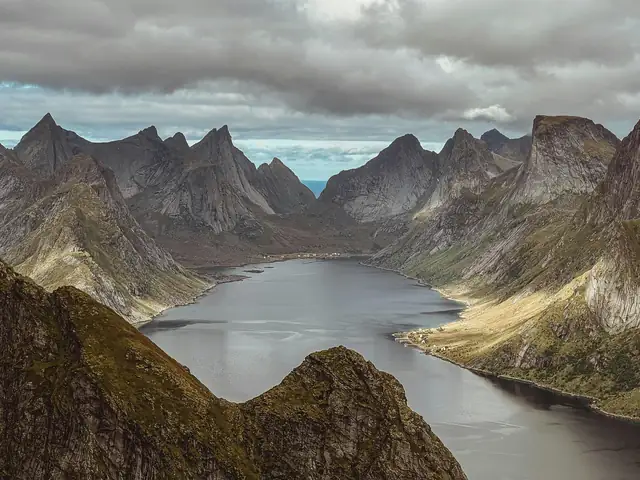 Stunning view of dramatic fjord and mountains near Reine, Norway, under cloudy sky.