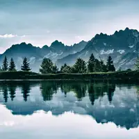 Stunning mountain landscape reflected in a serene lake under a clear sky.