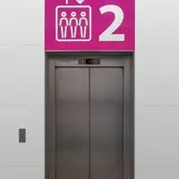 A modern elevator with vibrant pink signage indicating the second floor, captured indoors.