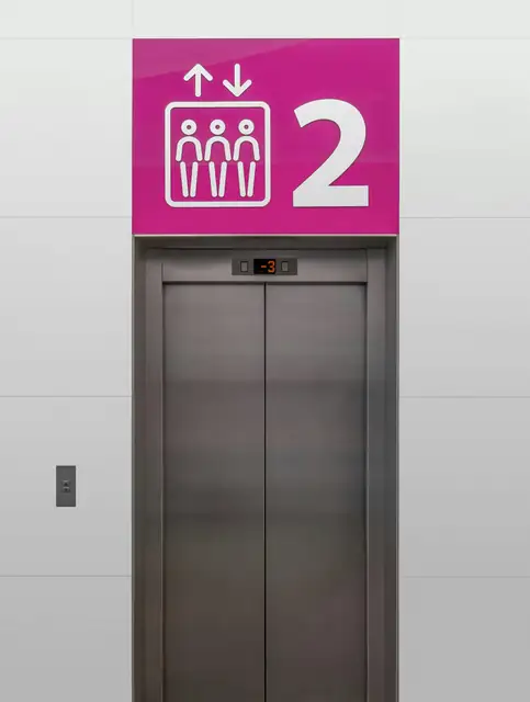 A modern elevator with vibrant pink signage indicating the second floor, captured indoors.