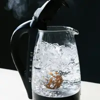 Close-up of an electric kettle with an egg boiling and steam rising, creating a dramatic scene.