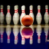 A striking close-up of a bowling ball approaching pins in a bowling alley.