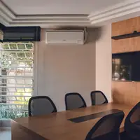 Spacious modern conference room featuring wooden table, chairs, TV, and air conditioning unit.