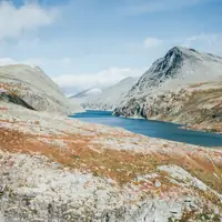 Discover the serene beauty of Norway's rugged mountains and tranquil lake.