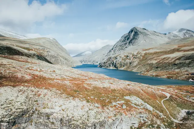 Discover the serene beauty of Norway's rugged mountains and tranquil lake.