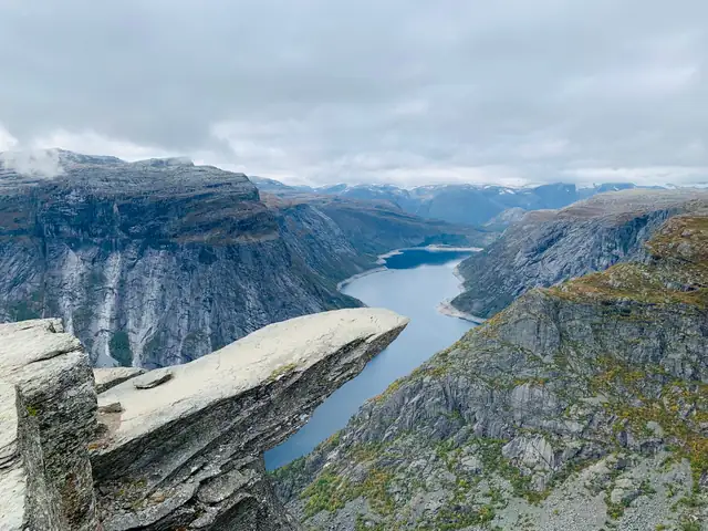 Breathtaking aerial view of the iconic Trolltunga rock formation overlooking a serene lake in Ullensvang, Norway.