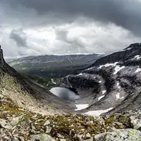 A dramatic landscape view of a snow-capped mountain and a serene lake during winter.