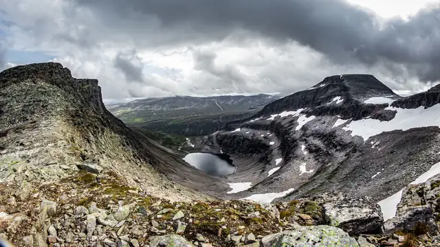 A dramatic landscape view of a snow-capped mountain and a serene lake during winter.