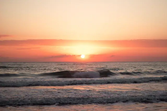 Tranquil sunrise over the ocean in Mersin, Türkiye with gentle waves and warm colors.