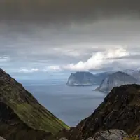 A stunning view of the Lofoten fjord surrounded by rocky mountains and a dramatic cloudy sky.
